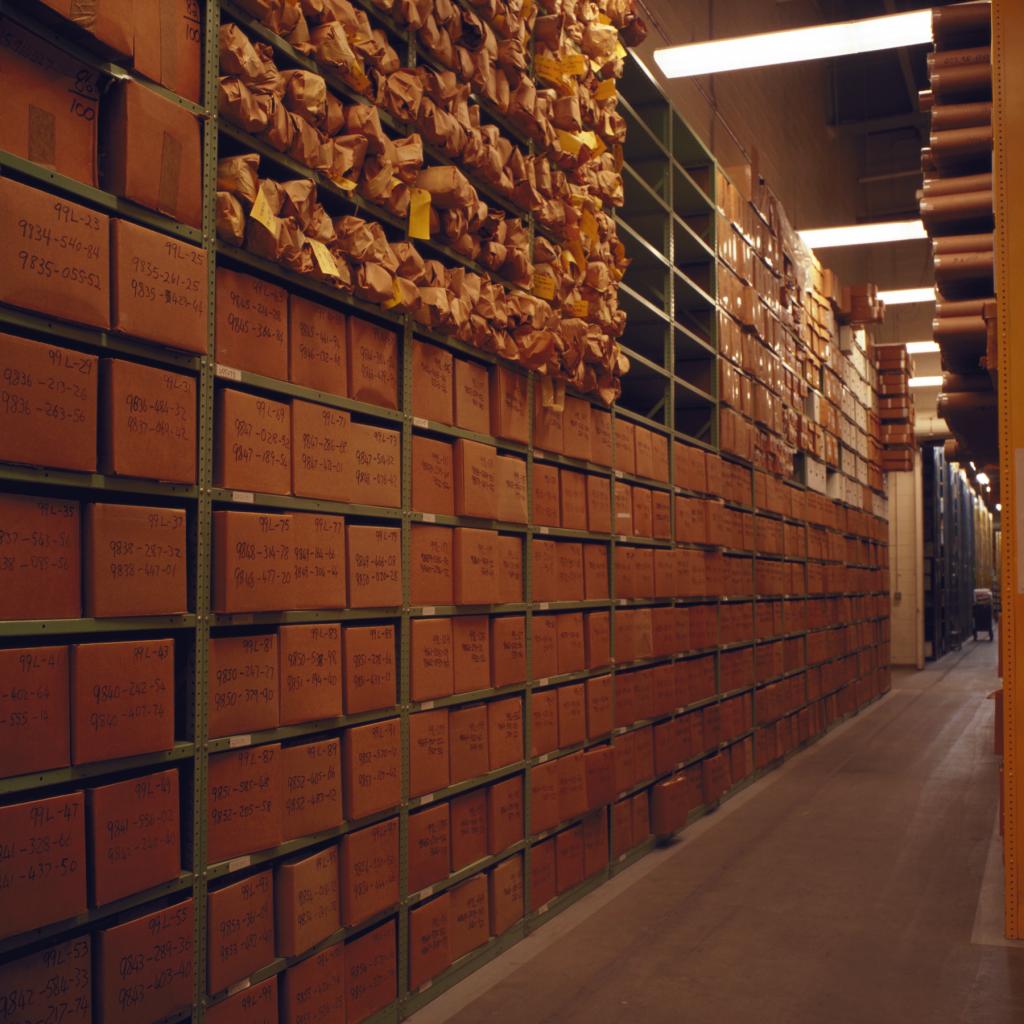 Rows of metal shelves filled with records boxes inside a United States National Archives facility